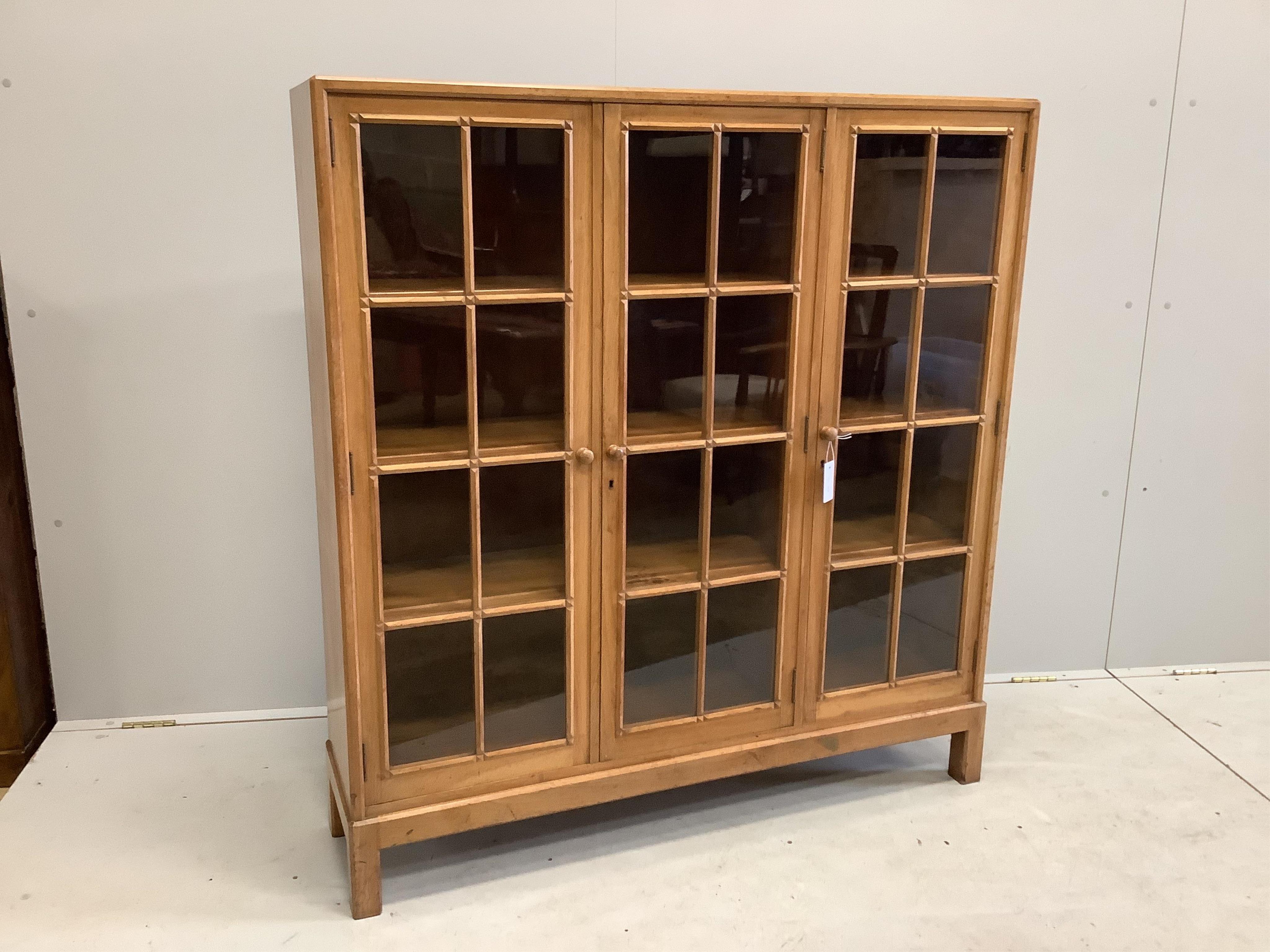 An early 20th century Heal & Son, London glazed walnut three door bookcase, width 122cm, depth 29cm, height 130cm. Condition - fair to good